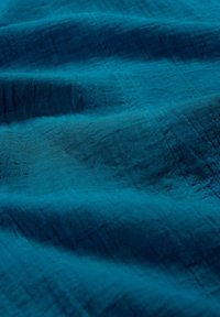 Textured teal fabric with subtle wrinkles and a soft sheen, showcasing a smooth, lightweight material suitable for draping or clothing.