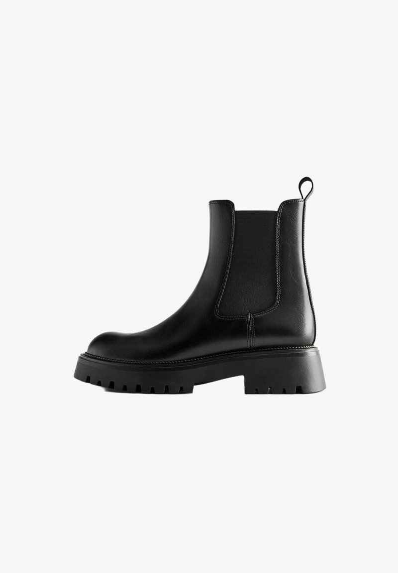 Bottine Chelsea en cuir noir avec panneaux latéraux élastiques, languette à l’arrière et semelle à crampons épaisse pour une meilleure adhérence et du style.