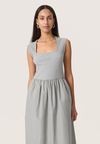 Hellgraues Kleid mit einem gerippten Oberteil und einem quadratischen Ausschnitt sowie einem gerafften Rock. Glatte Textur, kurze Ärmel und eine fließende Silhouette.