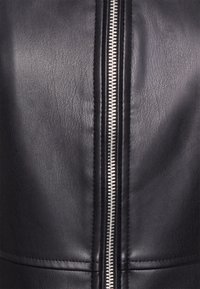 Svart läderjacka med en framträdande silverdragkedja, med en strukturerad yta och minimal sömnadsdetaljering.