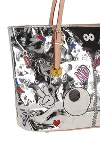 Bolso tote metálico plateado con diseños en relieve y detalles gráficos coloridos. Cuenta con asas beige y un detalle de cremallera en un lado.