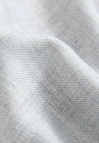 Tessuto a maglia grigio chiaro con una texture liscia, presenta un sottile motivo a spina di pesce, mostrando diverse sfumature all'interno della trama.