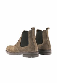 Stivali Chelsea in suede marrone con pannelli elastici neri sui lati, una linguetta e una suola in gomma resistente. Texture liscia con cuciture robuste.