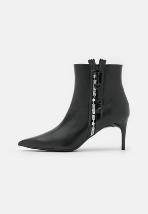 Bottine noire à bout pointu avec talon fin et fermeture éclair latérale présentant le logo Love Moschino sur la bande de la fermeture éclair.
