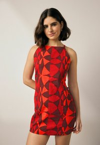 Rotes, gemustertes ärmelloses Kleid mit geometrischen Formen. Hergestellt aus strukturiertem Stoff mit taillierter Passform und hüftlangem Schnitt.