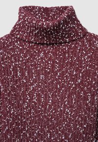 Maglione a collo alto in maglia color bordeaux con un motivo testurizzato, caratterizzato da macchie bianche sparse. Tessuto morbido di peso medio con colletto a costine.