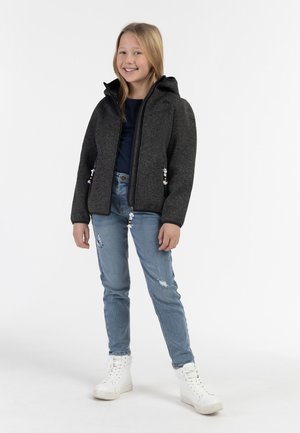 Giacca grigia con cappuccio, chiusura a zip e tasche laterali, abbinata a jeans blu strappati e sneakers bianche alte, texture liscia.