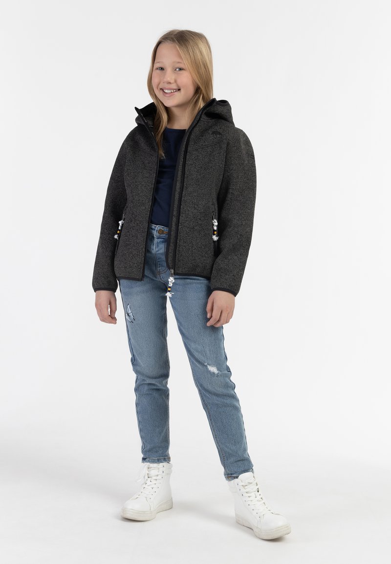 Chaqueta gris con capucha, cierre de cremallera y bolsillos laterales, combinada con jeans azules desgastados y zapatillas altas blancas, textura suave.