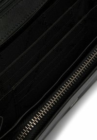 Portafoglio zip in nero con più slot per carte, realizzato in pelle e tessuto, con un interno testurizzato e un esterno liscio.