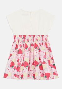 Λευκό τοπ με μανίκια τύπου καπελάκι, ελαστική μέση και ροζ φούστα με σχέδιο φράουλας και λεμονιού, διακοσμημένη με λουλουδένιες λεπτομέρειες.