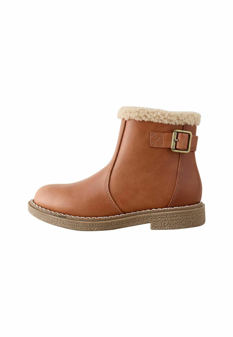 Braune Stiefelette mit Shearling-Kragen und seitlicher Schnalle, flache strukturierte Sohle, Obermaterial aus glattem Leder, seitlich betrachtet.
