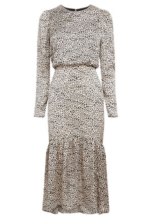 Robe beige à manches longues avec des pois noirs irréguliers, taille cintrée, ourlet froncé et encolure ronde avec fermeture par bouton au dos.