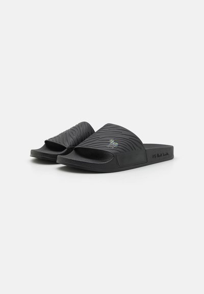 Black slide sandals with a textured, wavy upper, open toe design, and a raised logo, featuring a durable sole and minimalist style.
