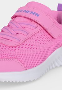 Baskets roses pour enfants avec tige en mesh, lacets élastiques, bride auto-agrippante, logo violet "Skechers" et semelle blanche texturée.