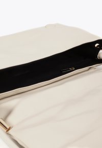 Borsa a mano in pelle crema con interno nero con zip e chiusura magnetica. Presenta una texture liscia e dettagli in metallo dorato.