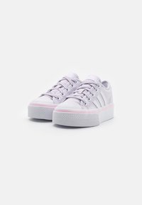 Lila canvas sneakers med en platt vit sula, med ett rosa rand, rund tå och snörning. Tre vita sidosträck pryder designen.