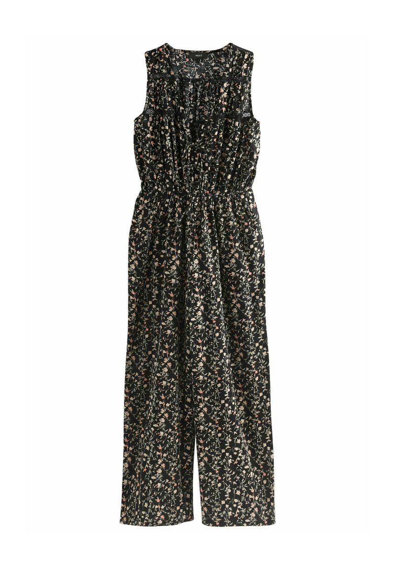 Jumpsuit floral en tissu noir avec une taille élastique, présentant un design sans manches et de petits motifs de fleurs colorées sur l'ensemble.