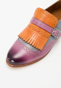 Leren schoen met een verloop van paars naar grijs, voorzien van oranje en paarse franjes, brogue-details en een zilveren gesp.