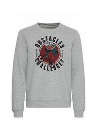 Harmaa collegepaita, jossa on pyöreä kuvio, jossa panda pyöräilee, ja teksti "Esteet ovat haasteita." Resorit hihansuissa ja kaula-aukossa.