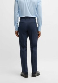 Navy dress pants with a tailored fit, featuring a subtle check pattern. Smooth fabric and a flat front design with standard back pockets.