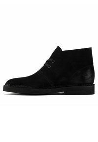 Black suede ankle boot featuring a rounded toe, two eyelet lacing system, and a flat rubber sole with stitching detail along the edge.