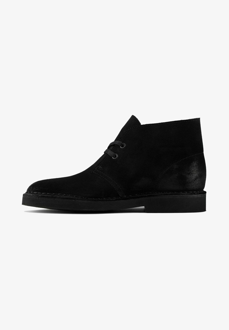 Black suede ankle boot featuring a rounded toe, two eyelet lacing system, and a flat rubber sole with stitching detail along the edge.