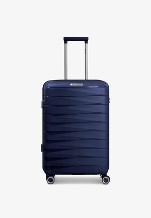 Valigia rigida blu scuro con scanalature orizzontali, quattro ruote e manico telescopico esteso color argento.