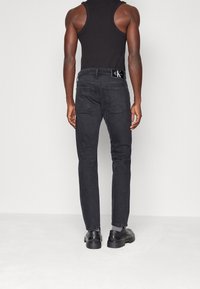 Svarta denimjeans med slim fit, med en klassisk fem-ficksdesign och silvriga detaljer. Midjebandet har en märkesetikett.