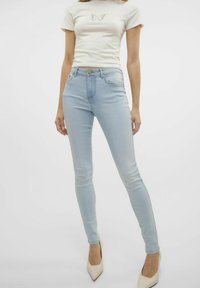 Jeans ajustados de color azul claro, confeccionados en denim, con un diseño ceñido que incluye cinco bolsillos, un botón frontal y detalles de costura sutiles.