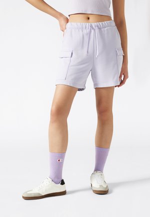 Pantaloni corti di cotone viola chiaro con vita regolabile, due tasche laterali e risvolti, abbinati a sneaker bianche e calzini lilla.