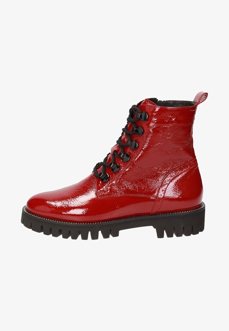 Botte de combat en cuir verni rouge brillant avec lacets noirs, œillets métalliques, semelle noire épaisse à crampons et languette de traction à l'arrière.