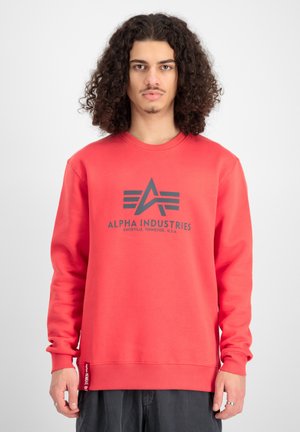 Rød sweatshirt lavet af blødt stof, med et logo-design i grå på brystet. Rund hals, lange ærmer og ribbede manchetter og kant.