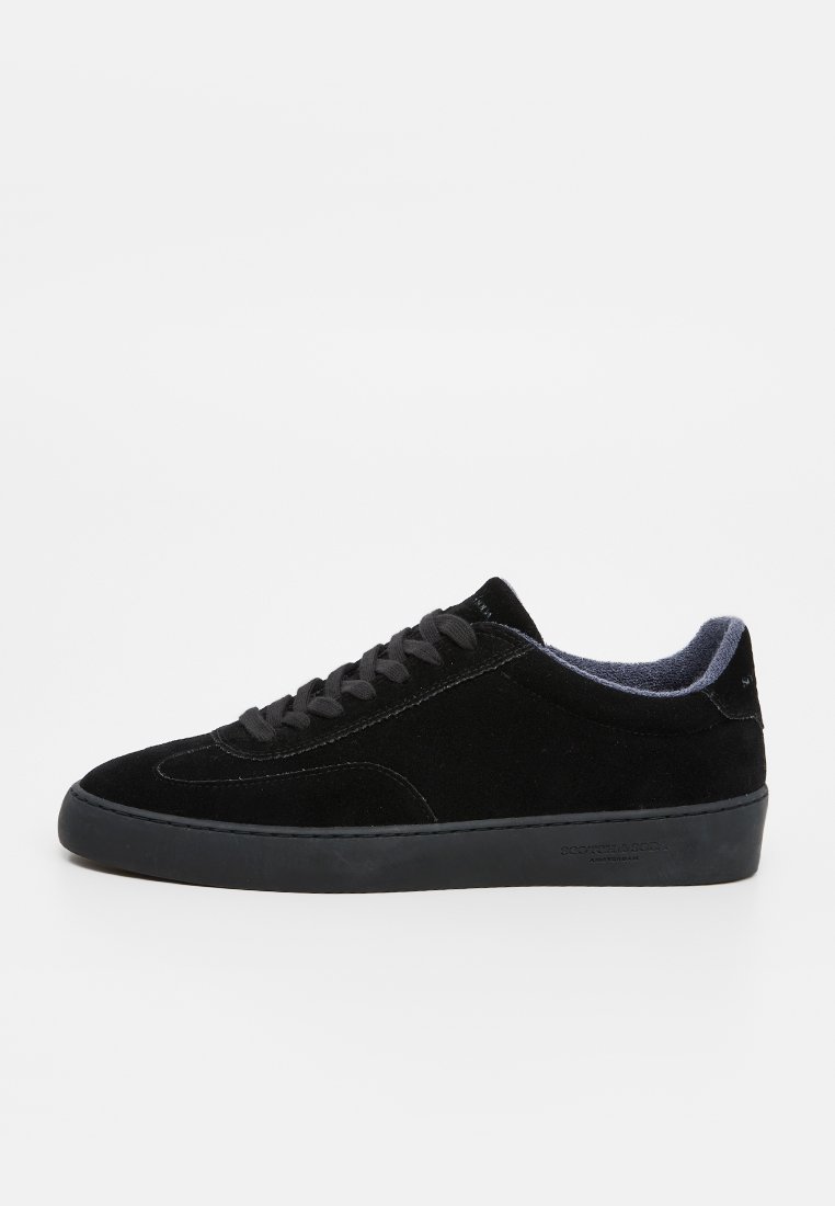 Zapatillas de ante negro con punta redondeada, diseño minimalista, suela negra de goma plana y cordones negros con un forro de tela texturizada.
