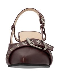 Zoccolo in pelle bordeaux con punta arrotondata, cinturino alla caviglia regolabile e occhielli decorativi in argento fissati da una fibbia metallica. Suola piatta.