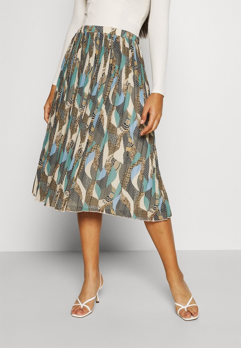 Jupe midi plissée présentant un mélange de motifs bleus, noirs et beiges avec des formes abstraites et des textures contrastées. Taille élastique.
