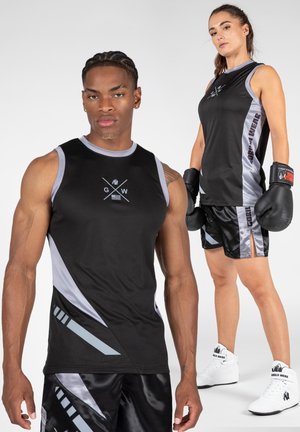 Zwart sportief tanktop met grijze accenten en logo; gecombineerd met zwarte glanzende shorts met geometrische patronen en zijsplitten.