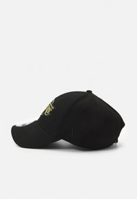 Gorra negra con visera curva, que presenta un logo dorado en el frente, dos orificios de ventilación a cada lado y una tela texturizada.