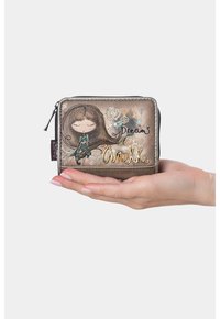 Una mano tiene un piccolo portafoglio in bronzo con cerniera, raffigurante una ragazza dei cartoni, accenti floreali, la parola "Sogni" e il logo dorato "Anekke".