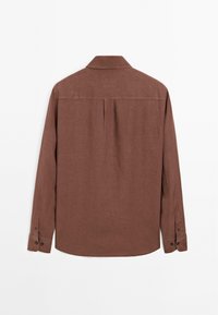 Chemise marron à manches longues avec poignets boutonnés, empiècement au dos et pli central dans le dos, présentée sur fond blanc.