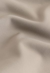 Close-up of soft, beige fabric with subtle folds and a smooth, slightly textured surface.