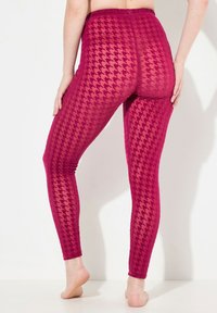 Leggings magenta realizzati in un tessuto traslucido e texturizzato con motivo houndstooth. Design a vita alta con elastico in vita.