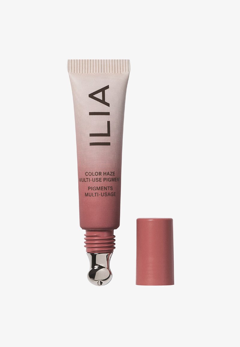 Różowa i beżowa tubka z zaokrąglonym metalowym wierzchołkiem aplikatora. Napis na tubce: "ILIA Color Haze Multi-Use Pigment." Korek jest cylindryczny i różowy.