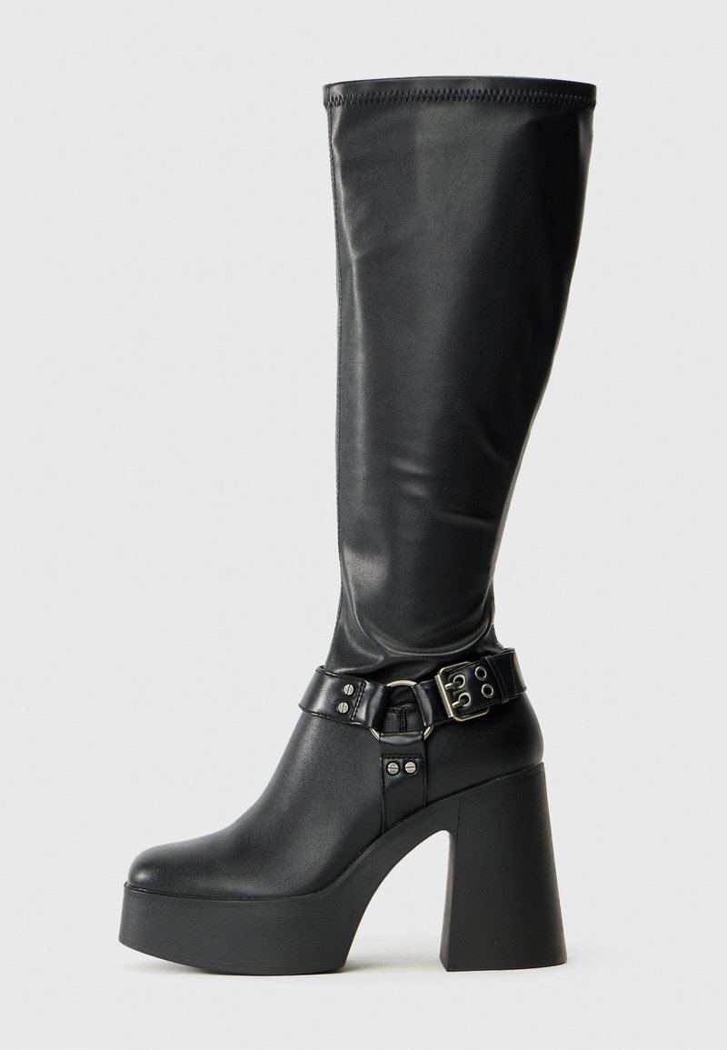 Bottes noires montantes à plateforme avec une finition brillante, dotées d'un large talon bloc et d'une sangle à boucle au niveau de la cheville.