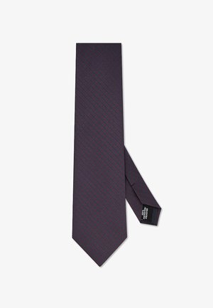 Granatowy jedwabny krawat z drobnym czerwonym wzorem geometrycznym i metką wskazującą na 100% poliester.