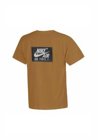 Camiseta de algodón marrón con un gráfico rectangular negro en la parte posterior, que presenta "Nike Air Force 1" en texto blanco en negrita y el logo de Nike.