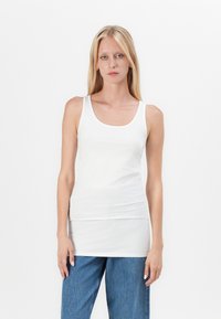 Witte tanktop van rekbare katoen, met een ronde halslijn en een slim fit ontwerp. Gecombineerd met losse blauwe spijkerbroek.
