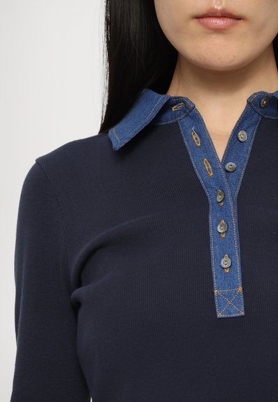 Tengerészkék bordás póló ing denim gallérral, kontrasztos színű gombokkal és díszvarrással az elején.