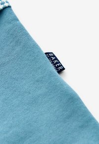 Jasnoniebieska bawełniana tkanina o gładkiej fakturze, z białym geometrycznym wzorem oraz niebieską etykietą z napisem "BAKER by Ted Baker".