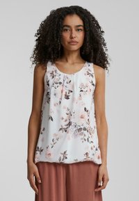 Top sans manches en tissu léger, présentant un fond blanc orné de motifs floraux roses et bruns, avec un col rond et des détails plissés.