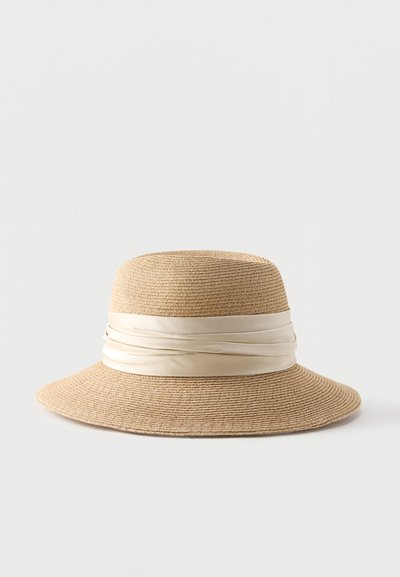 Μπεζ υφαντό ψάθινο καπέλο με φαρδιά γείσο και κρεμ σατέν κορδέλα τυλιγμένη γύρω από το στέμμα.